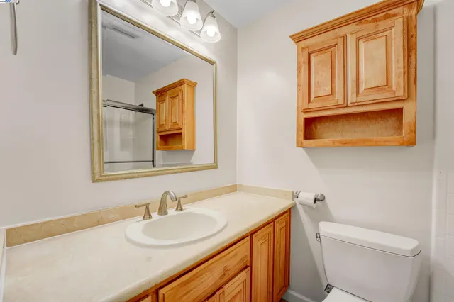 a bathroom with a granite countertop sink vanity mirror and toilet