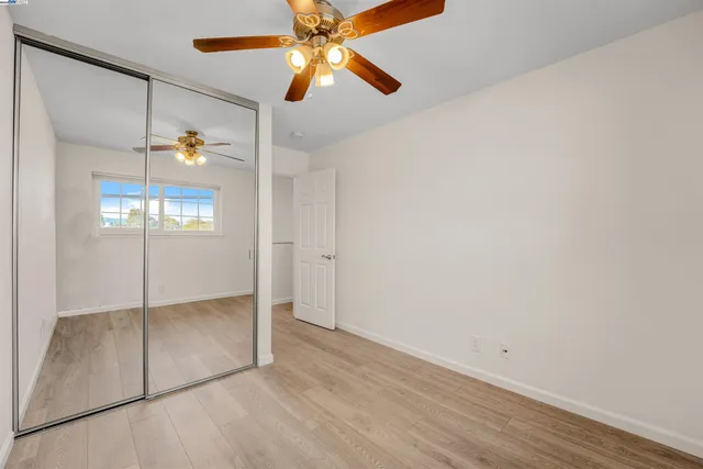 an empty room with windows and fan