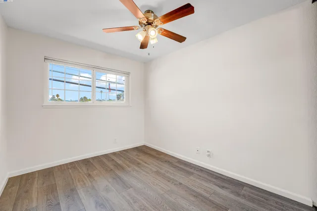 an empty room with a window and a fan