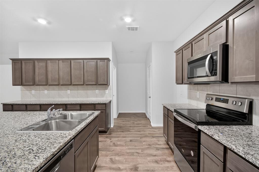 827 Rustic Way Royse City, TX 75189 - Photo 17 of 32 a kitchen with stainless steel appliances granite countertop a sink stove and microwave