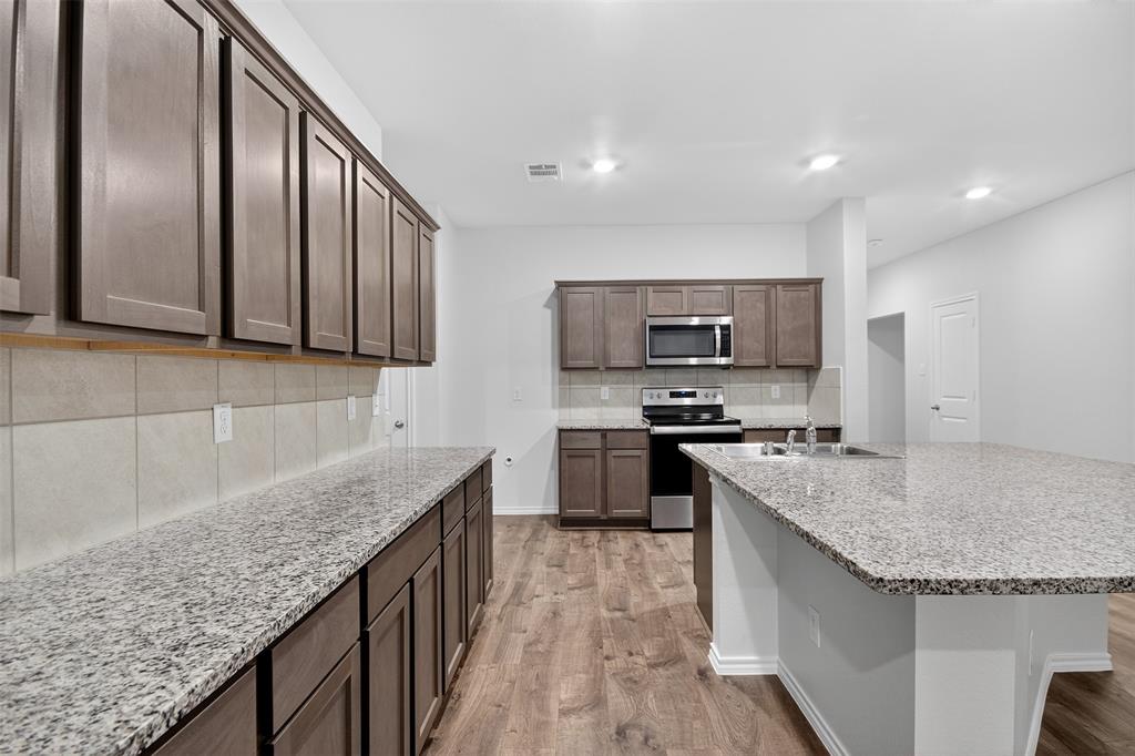827 Rustic Way Royse City, TX 75189 - Photo 19 of 32 a kitchen with stainless steel appliances granite countertop a sink a stove and a microwave