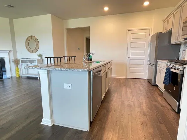 a kitchen with stainless steel appliances granite countertop a refrigerator a stove and a wooden floors