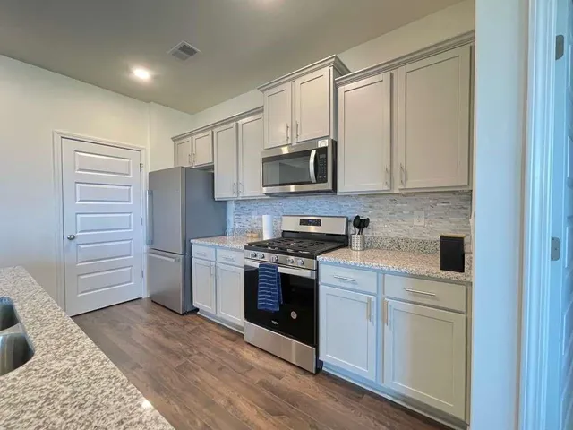 a kitchen with stainless steel appliances granite countertop a refrigerator and a stove top oven