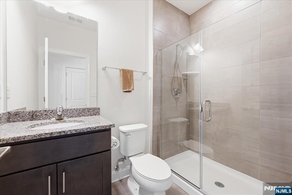 905 Abbe Road Little Falls, NJ 07424 - Photo 21 of 26 a bathroom with a granite countertop sink toilet a mirror and shower