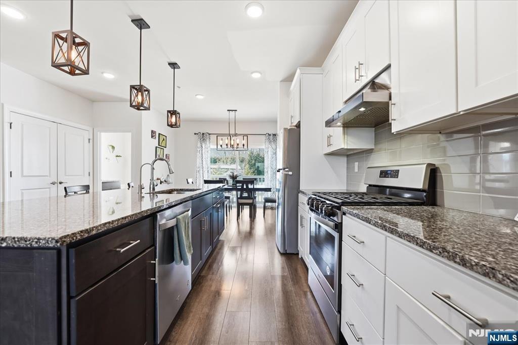 905 Abbe Road Little Falls, NJ 07424 - Photo 4 of 26 a kitchen with stainless steel appliances granite countertop a stove a sink and a granite counter tops with white cabinets