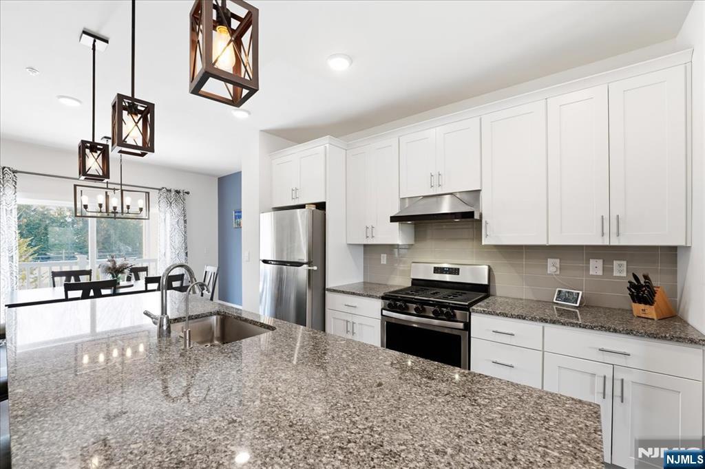 905 Abbe Road Little Falls, NJ 07424 - Photo 6 of 26 a kitchen with granite countertop a stove a sink and a refrigerator