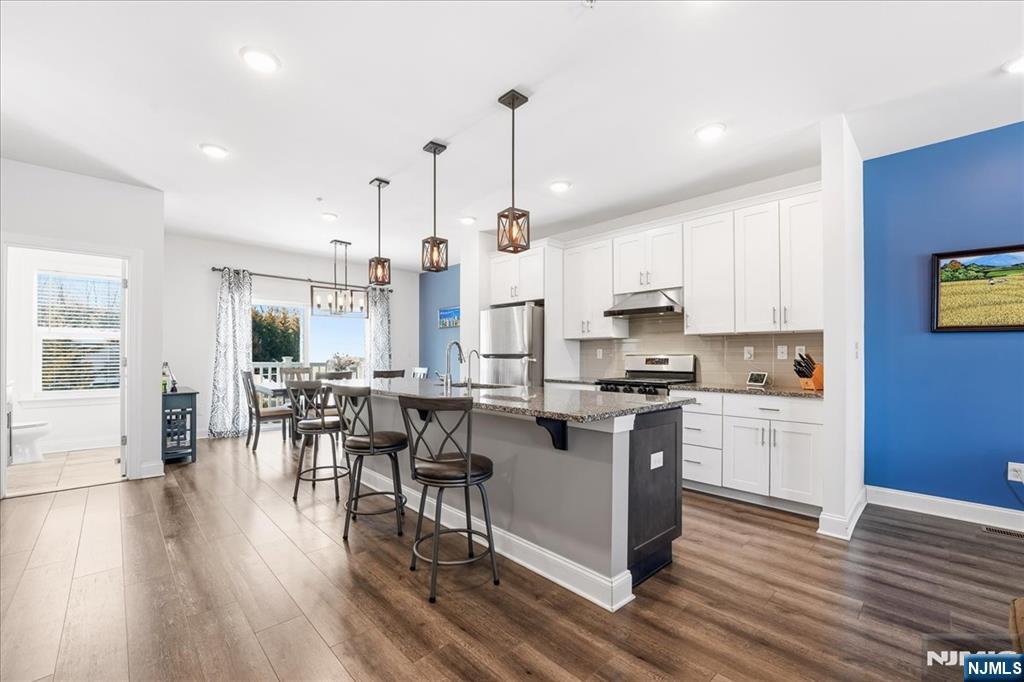 905 Abbe Road Little Falls, NJ 07424 - Photo 7 of 26 a open kitchen with granite countertop a stove a sink dishwasher a refrigerator and white cabinets with wooden floor