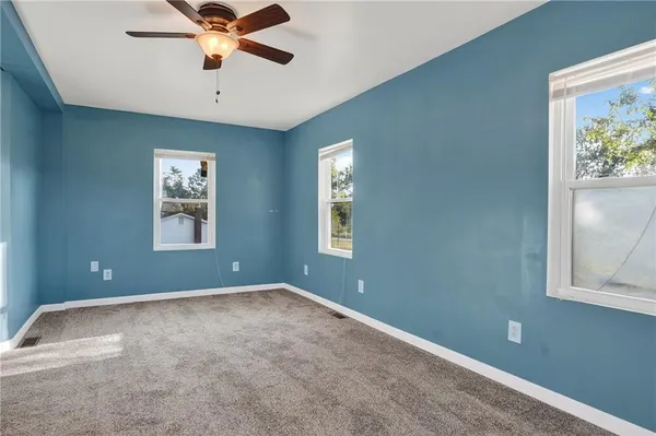 an empty room with windows and fan