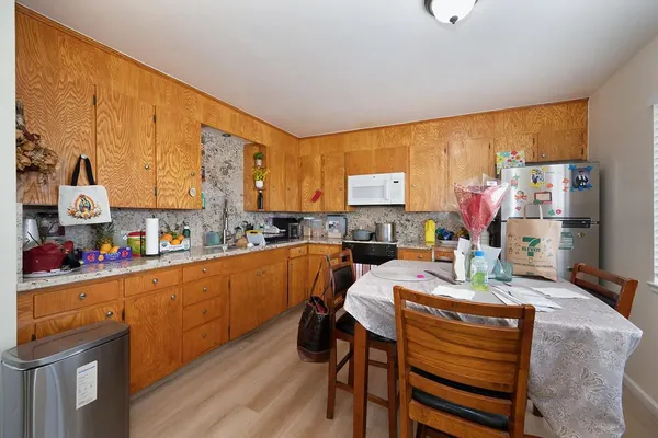 a kitchen with stainless steel appliances sink refrigerator dining table and chairs