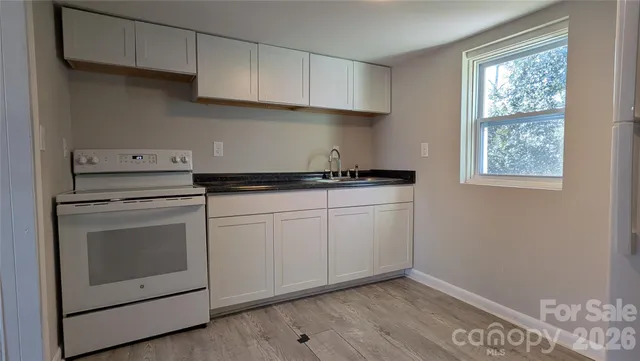 a kitchen with granite countertop white cabinets and white appliances