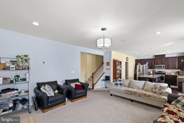 a living room with furniture kitchen view and a chandelier