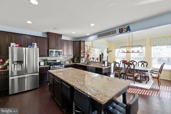 a kitchen with stainless steel appliances granite countertop a refrigerator a stove top oven a sink a dining table and chairs