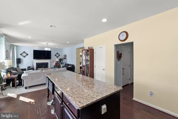 a living room with stainless steel appliances granite countertop furniture wooden floor and a view of kitchen