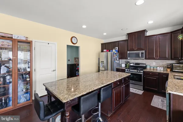 a kitchen with stainless steel appliances granite countertop a stove a refrigerator a sink a dining table and chairs