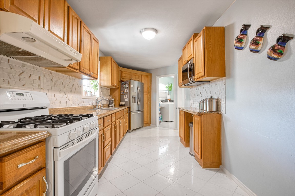13117 Player Street Houston, TX 77045 - Photo 10 of 36 a kitchen with stainless steel appliances granite countertop a stove a sink and a refrigerator
