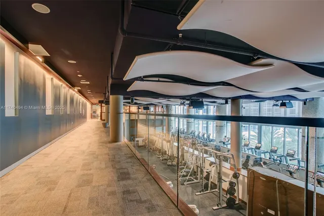 a hallway with a view of the living room and chandelier