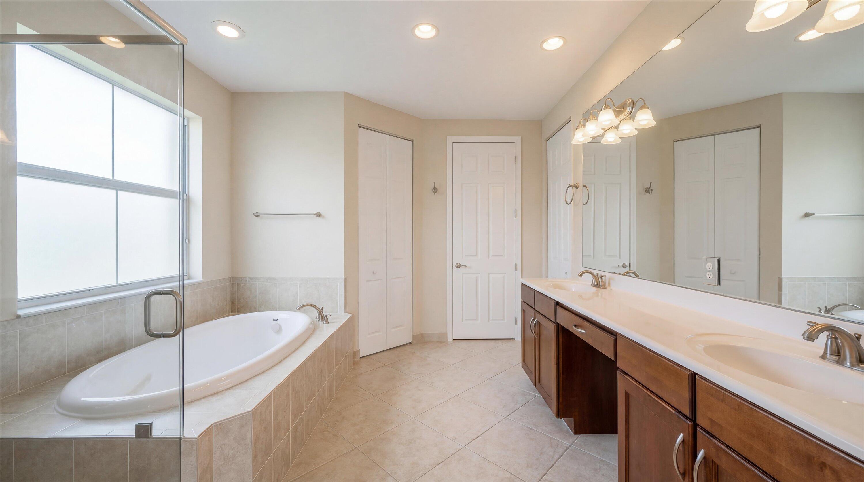 3072 Payson Way Wellington, FL 33414 - Photo 20 of 43 a spacious bathroom with a double vanity sink large mirror and a bathtub
