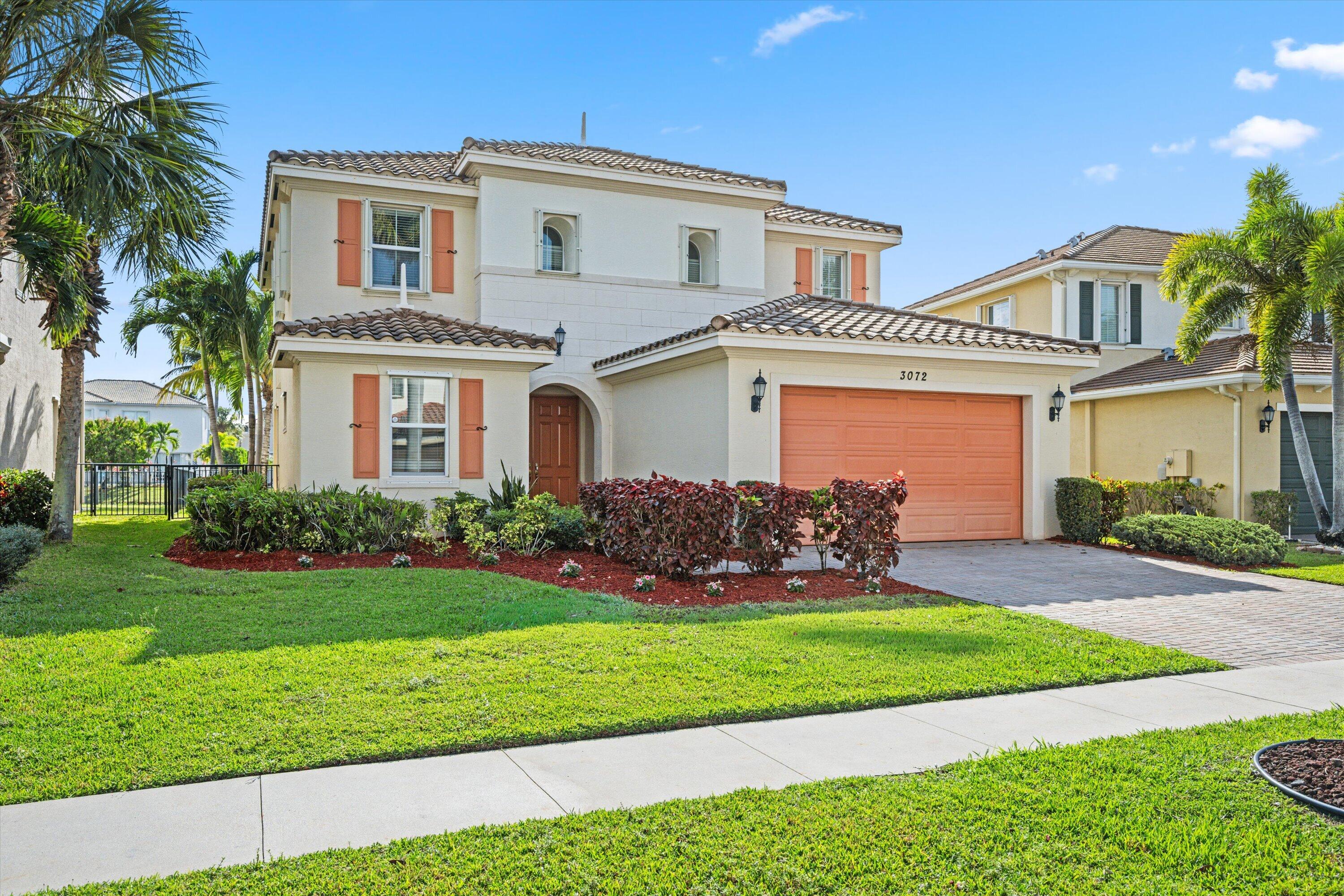 3072 Payson Way Wellington, FL 33414 - Photo 2 of 43 a front view of a house with a yard and garage