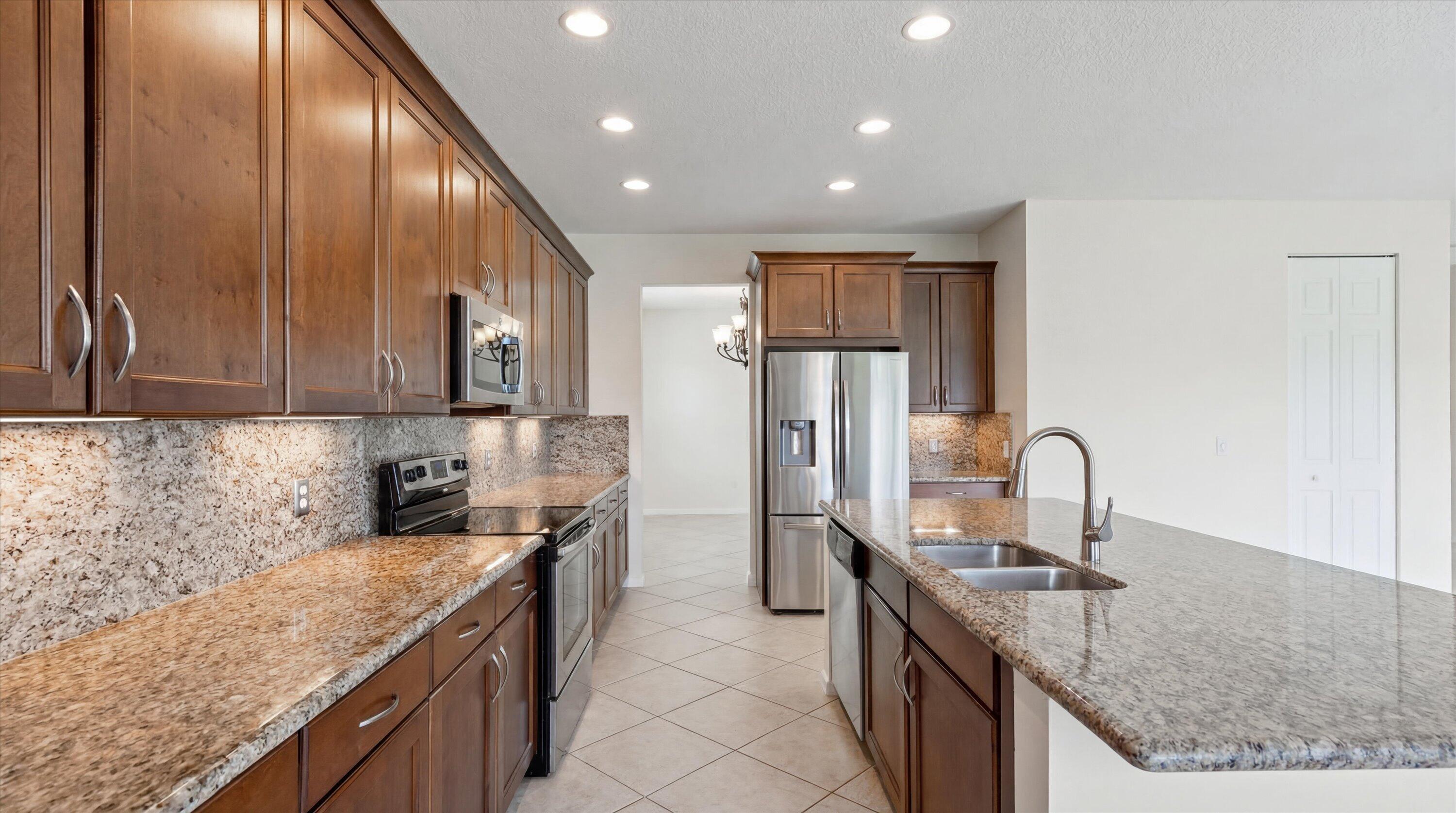 3072 Payson Way Wellington, FL 33414 - Photo 7 of 43 a kitchen with granite countertop stainless steel appliances a sink stove and refrigerator