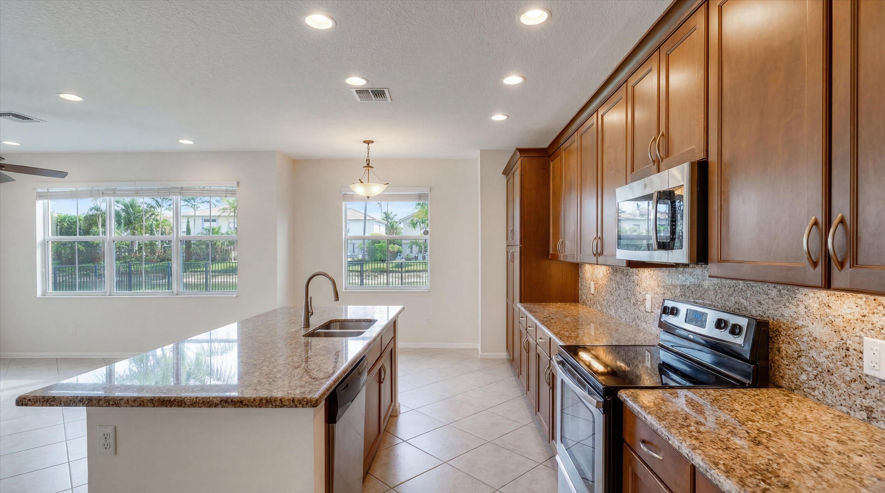 3072 Payson Way Wellington, FL 33414 - Photo 8 of 43 a kitchen with granite countertop kitchen island stainless steel appliances a sink stove and cabinets