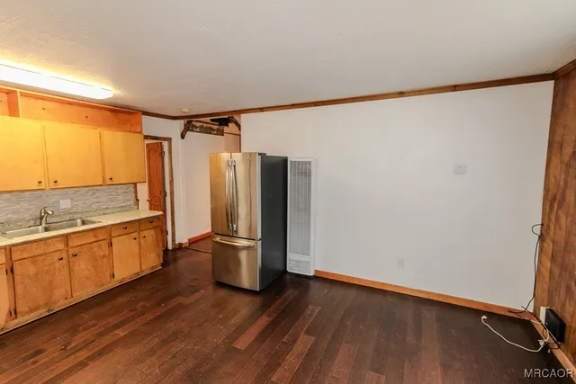 a view of a kitchen with a refrigerator and wooden floor
