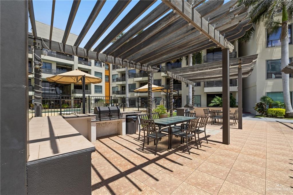 813 Travis Street, Unit 203 Mission, TX 78572 - Photo 24 of 30 a view of a patio with a dining table and chairs under an umbrella with a barbeque