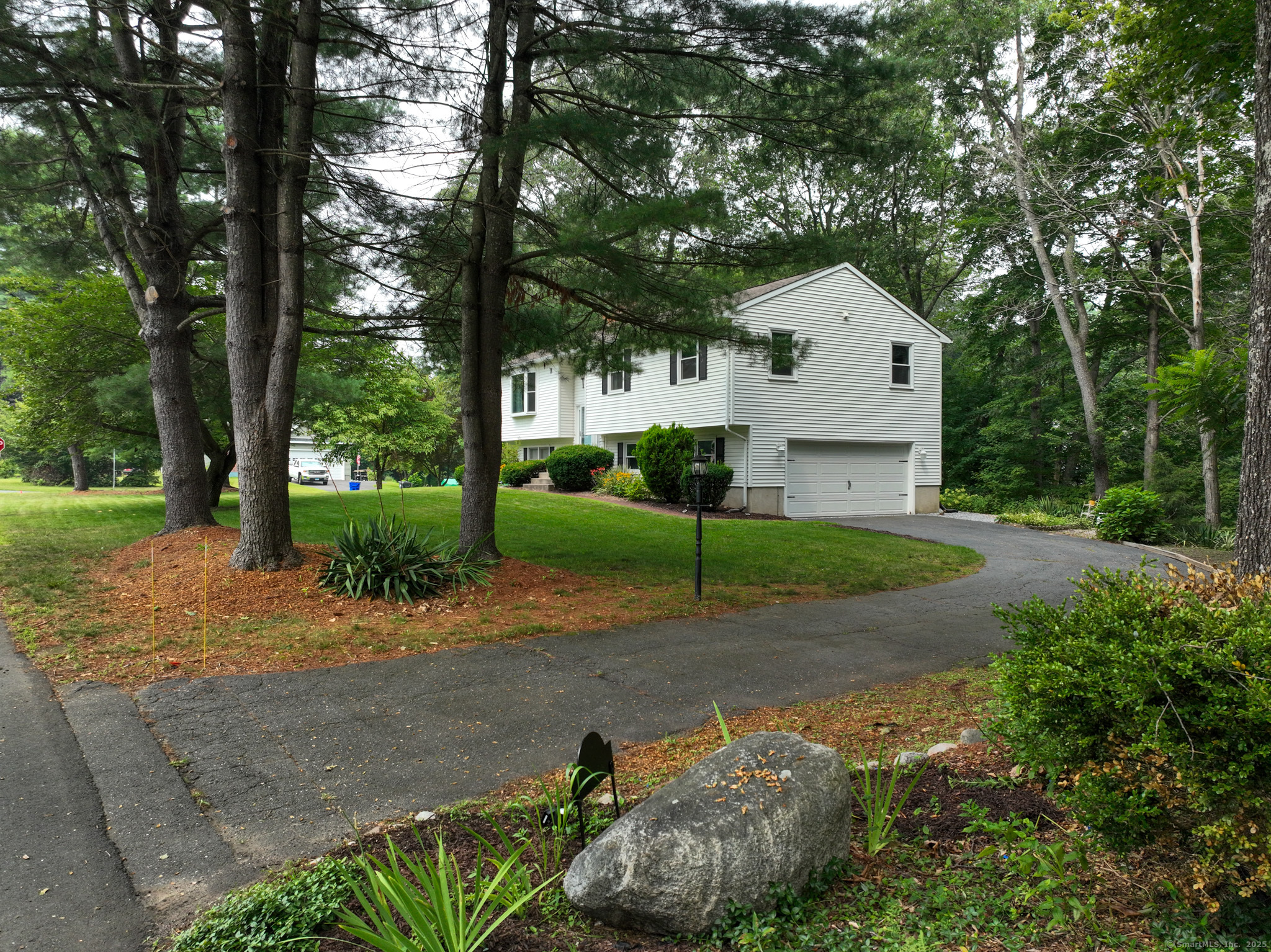 a view of a white house with a yard plants and tree