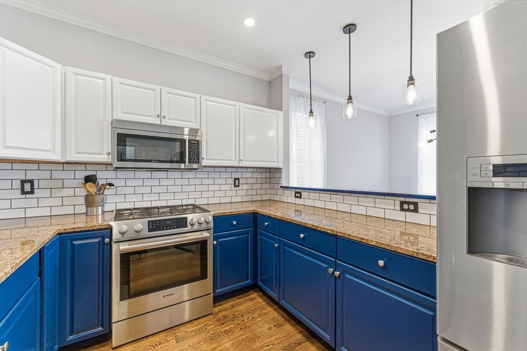 6 Millmont Street, Unit 6 Boston, MA 02119 - Photo 16 of 42 a kitchen with stainless steel appliances granite countertop a sink a stove a microwave and wooden cabinets
