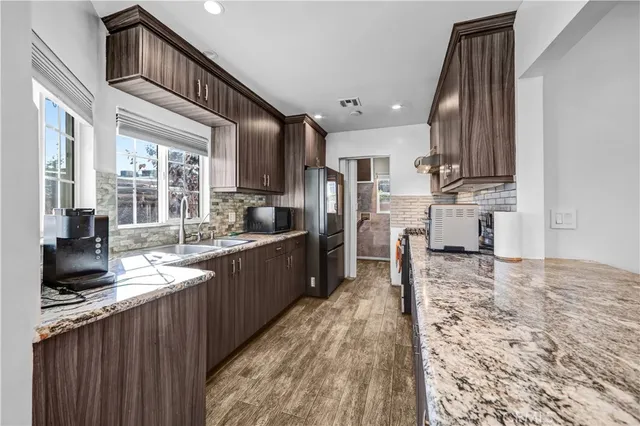 a kitchen with kitchen island granite countertop a stove top oven a sink a counter space and cabinets