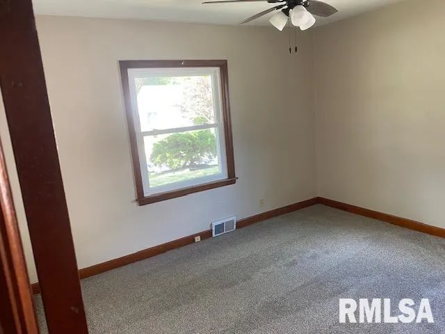 an empty room with windows and fan