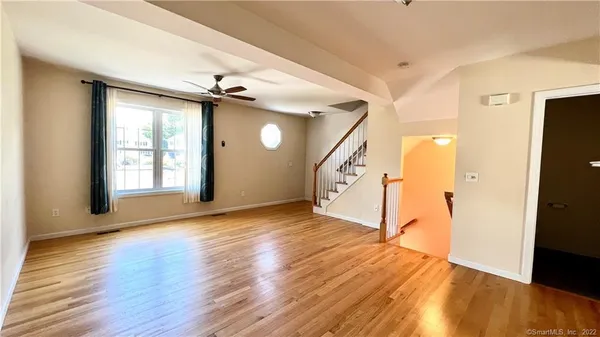 a view of an empty room with wooden floor and a window