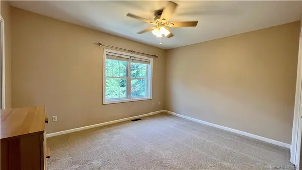an empty room with windows and fan