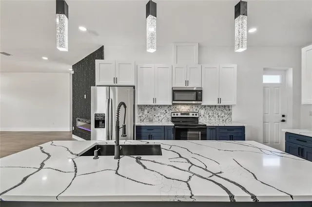 a kitchen with stainless steel appliances kitchen island granite countertop a stove a refrigerator a sink a dining table and chairs with wooden floor