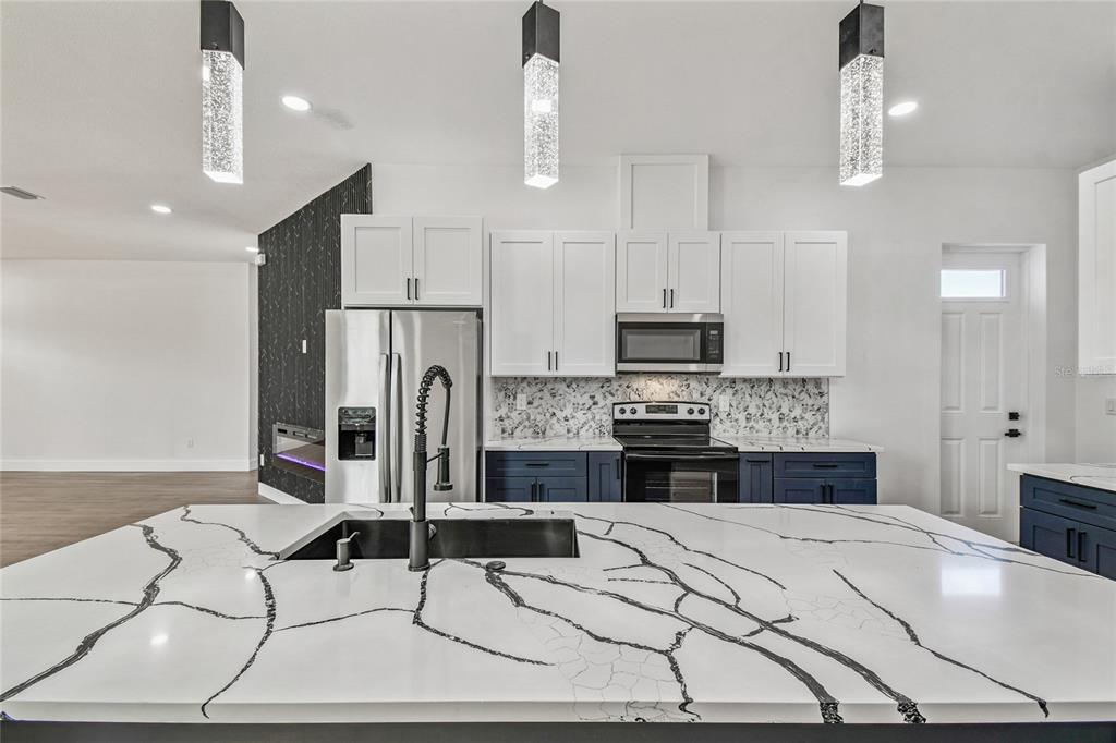 310 Waterfall Drive Spring Hill, FL 34608 - Photo 11 of 40 a kitchen with stainless steel appliances kitchen island granite countertop a stove a refrigerator a sink a dining table and chairs with wooden floor