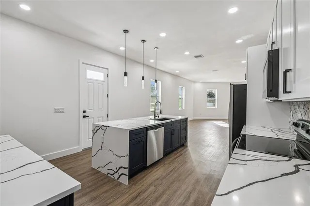 a large kitchen with stainless steel appliances a large counter top a sink a stove and a refrigerator