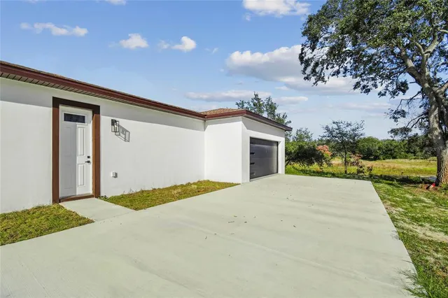 a view of an house with backyard and bushes