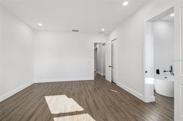 an empty room with wooden floor and white walls