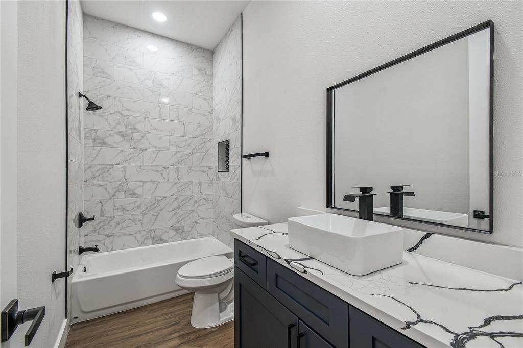 310 Waterfall Drive Spring Hill, FL 34608 - Photo 33 of 40 a bathroom with a granite countertop sink toilet a large mirror and shower