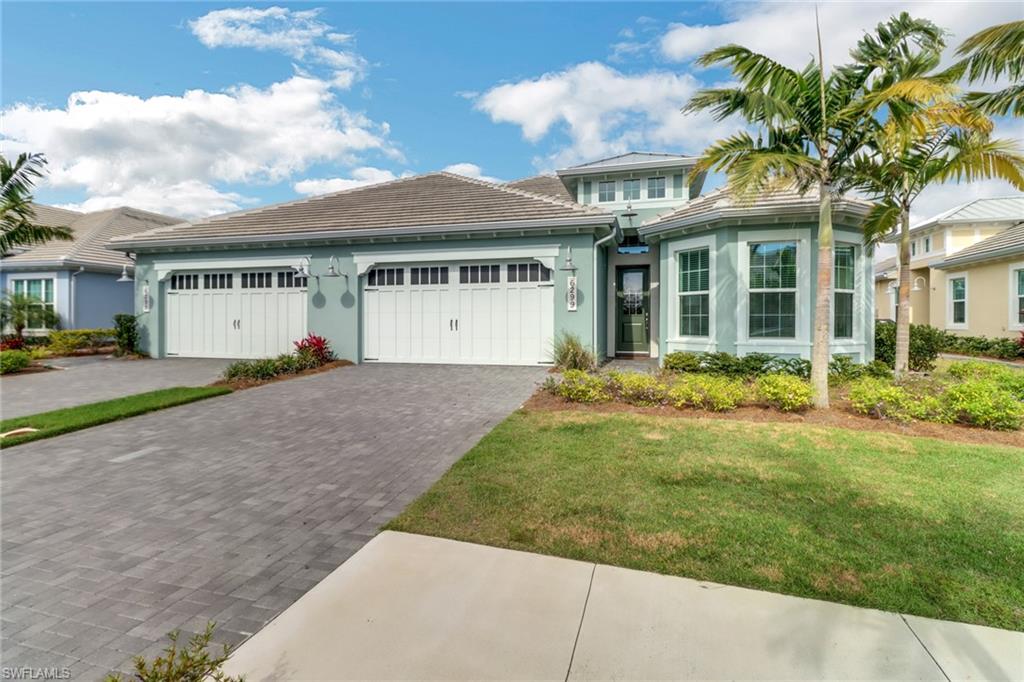 View of front of property featuring a garage, a tile roof, decorative driveway, a front yard, and stucco siding