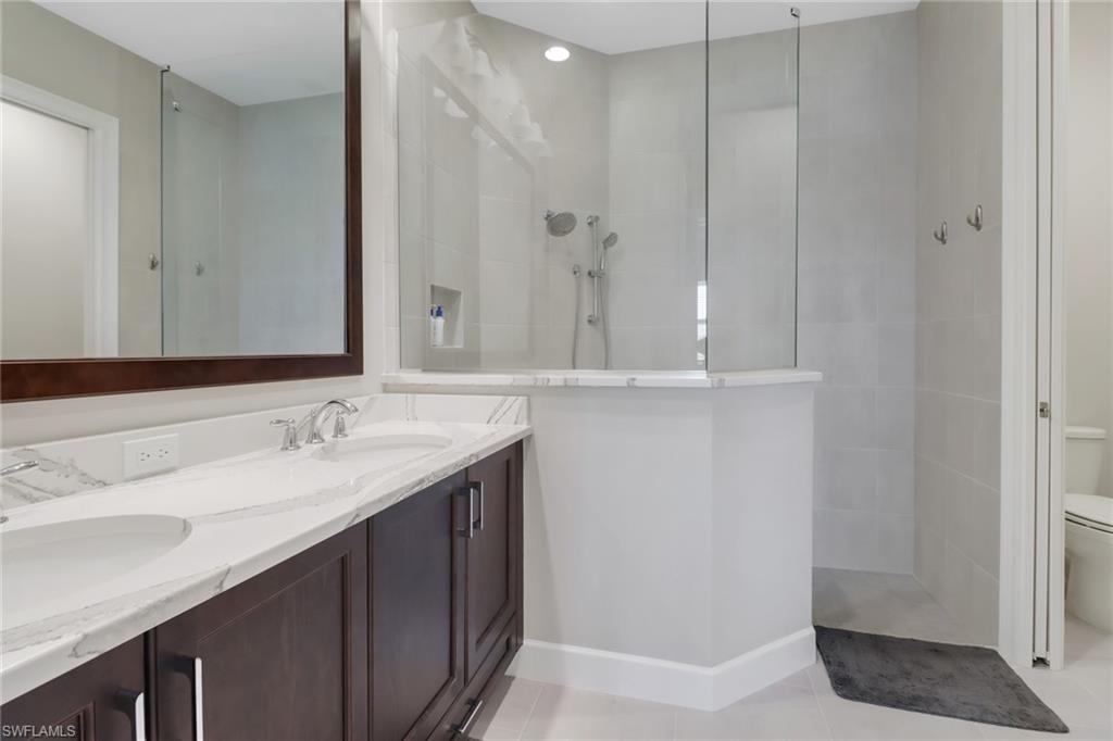 6299 Arriba Avenue Naples, FL 34113 - Photo 11 of 26 Bathroom with a walk in shower, tile patterned flooring, toilet, baseboards, and double vanity
