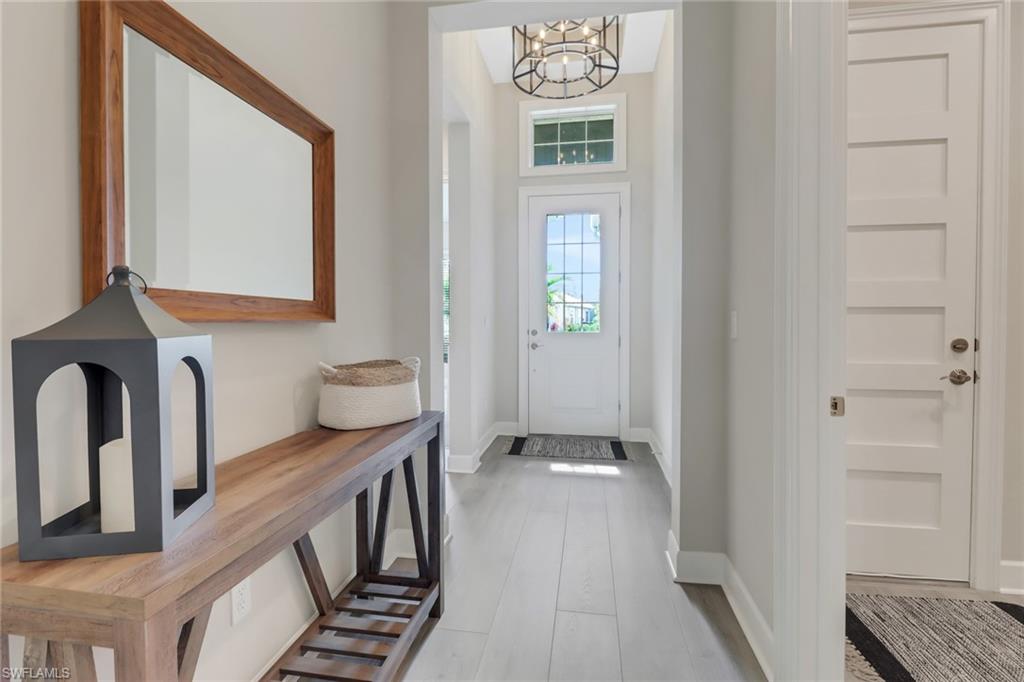 6299 Arriba Avenue Naples, FL 34113 - Photo 15 of 26 Foyer entrance featuring baseboards, wood finished floors, and an inviting chandelier