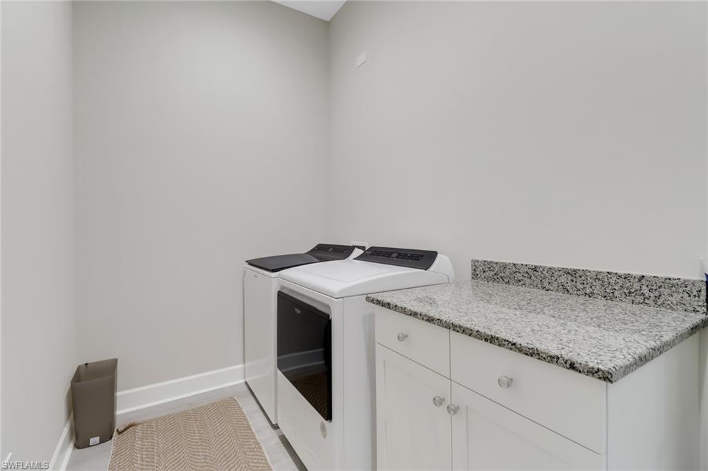 6299 Arriba Avenue Naples, FL 34113 - Photo 19 of 26 Clothes washing area featuring cabinet space, washer and clothes dryer, and baseboards