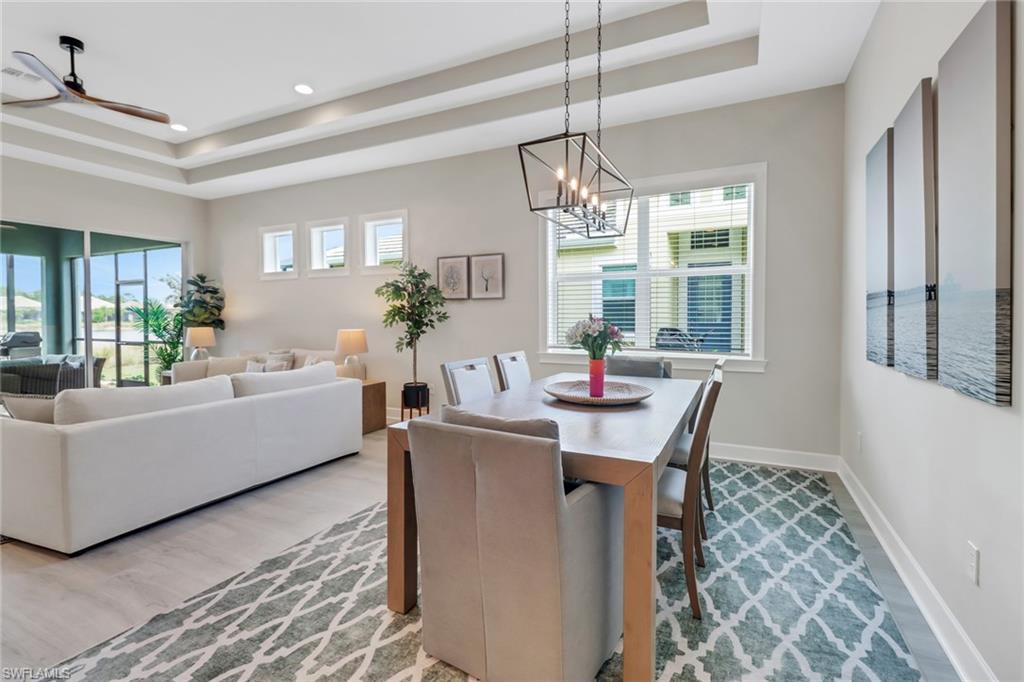 6299 Arriba Avenue Naples, FL 34113 - Photo 6 of 26 Dining space with a tray ceiling, recessed lighting, light wood-style flooring, baseboards, and ceiling fan with notable chandelier