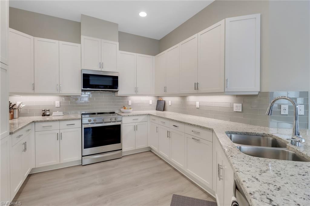 6299 Arriba Avenue Naples, FL 34113 - Photo 8 of 26 Kitchen featuring white cabinets, backsplash, stainless steel appliances, and a sink