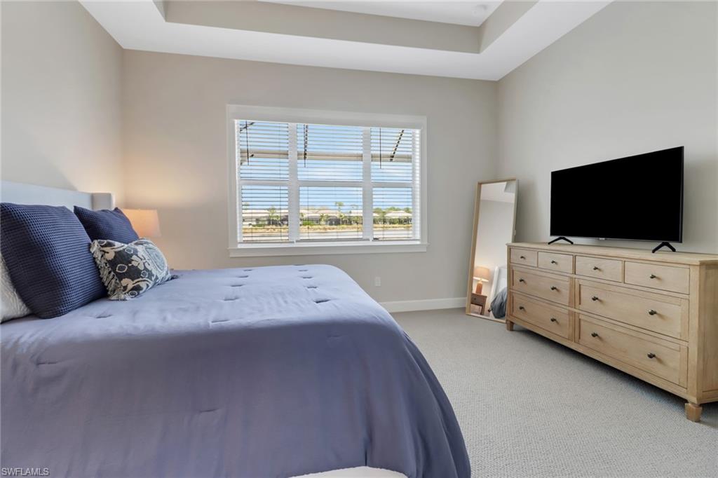 6299 Arriba Avenue Naples, FL 34113 - Photo 10 of 26 Bedroom featuring baseboards, a raised ceiling, and light colored carpet