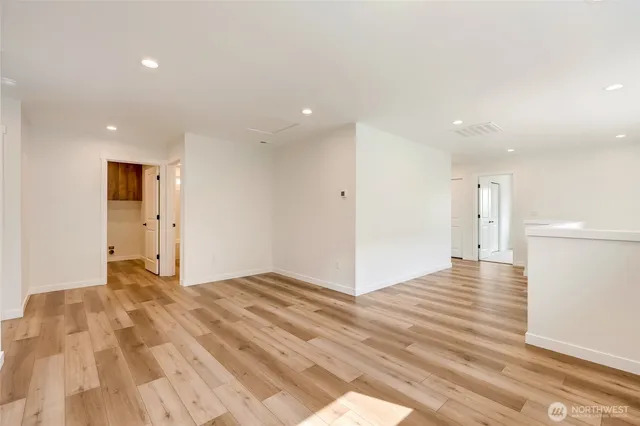 a view of an empty room with wooden floor and a ceiling fan