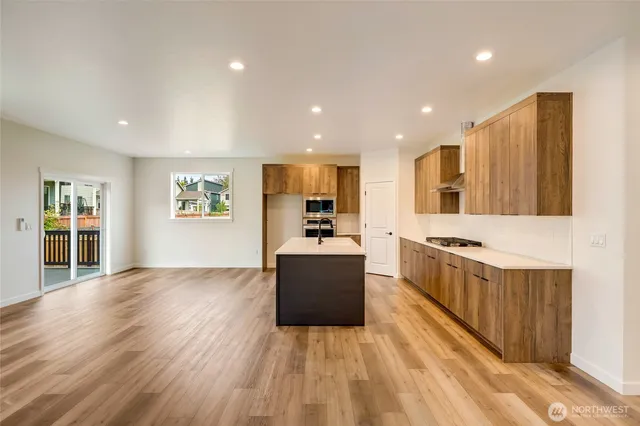 a large kitchen with stainless steel appliances a large counter top a stove and a wooden floors