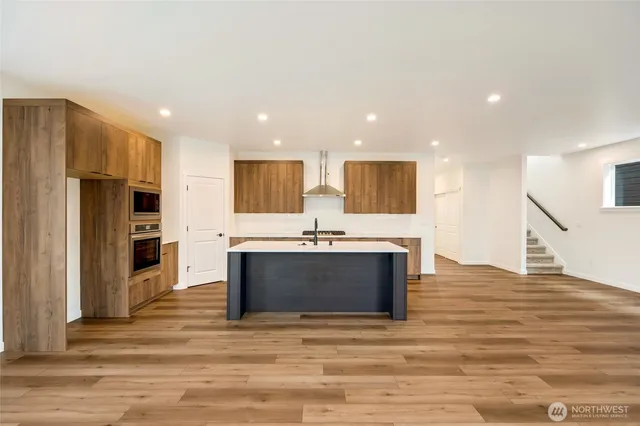 a view of kitchen with kitchen island granite countertop a stove and a sink