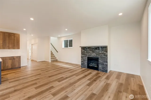 a view of an empty room with wooden floor fireplace and a window