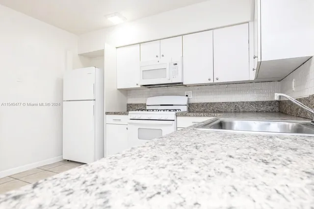 a kitchen with granite countertop a refrigerator and a stove top oven